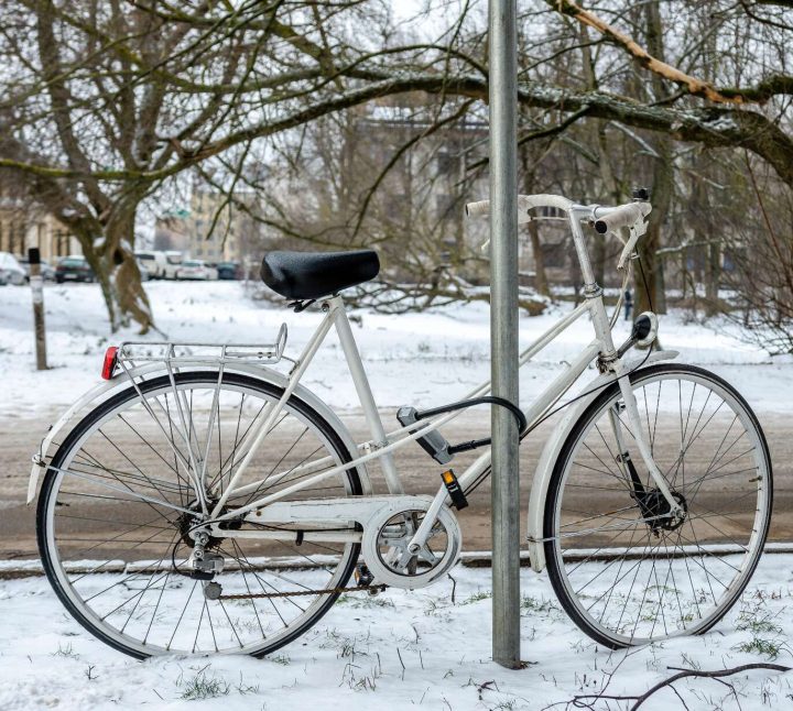 white-bicycle-with-lock-locked-at-street-sign-city-winter-landscape-bicycle-street-city-white-locked-t20-1qo1zv